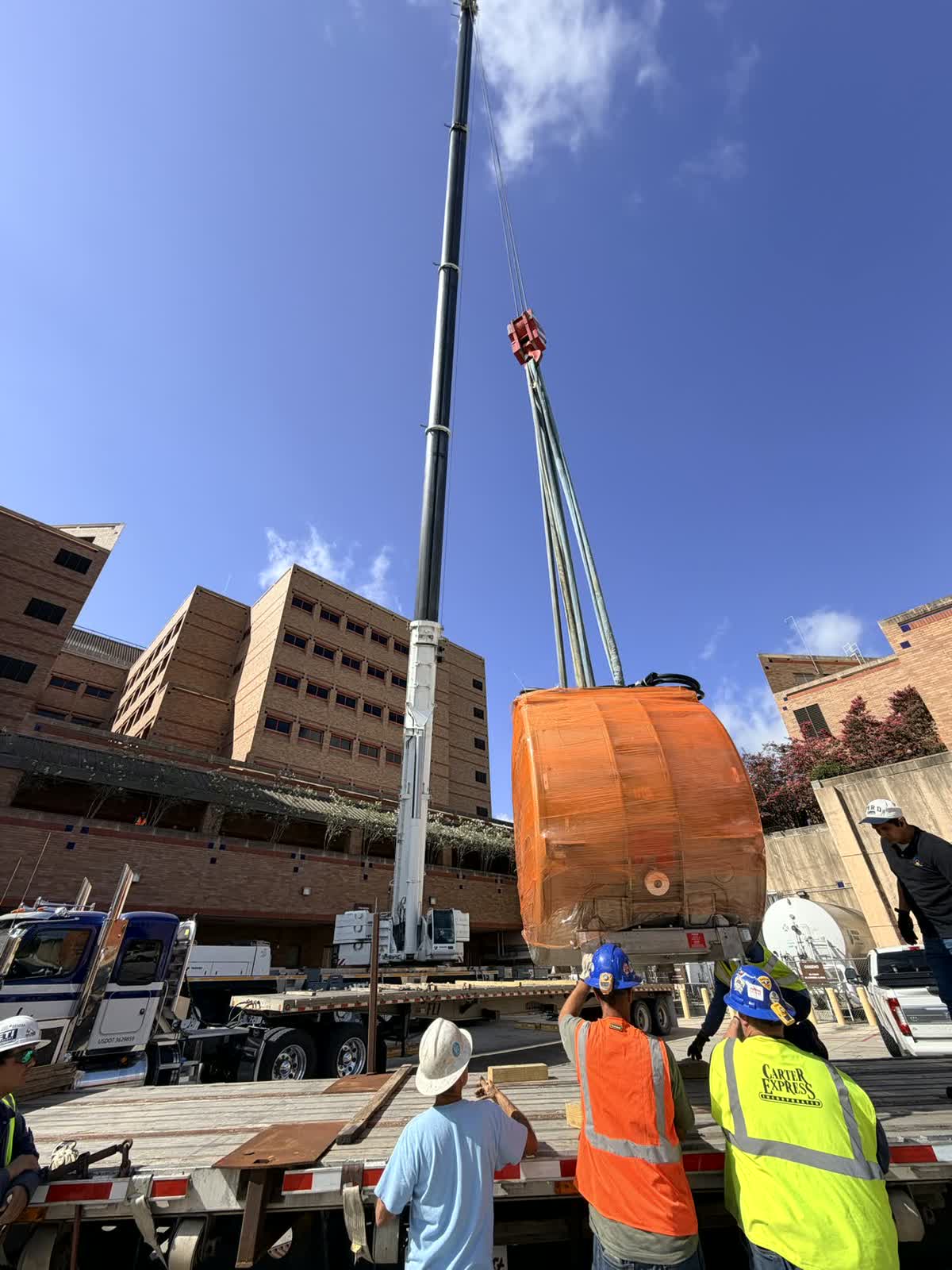 Two units rigged and lifted in one pick against a blue Texas sky