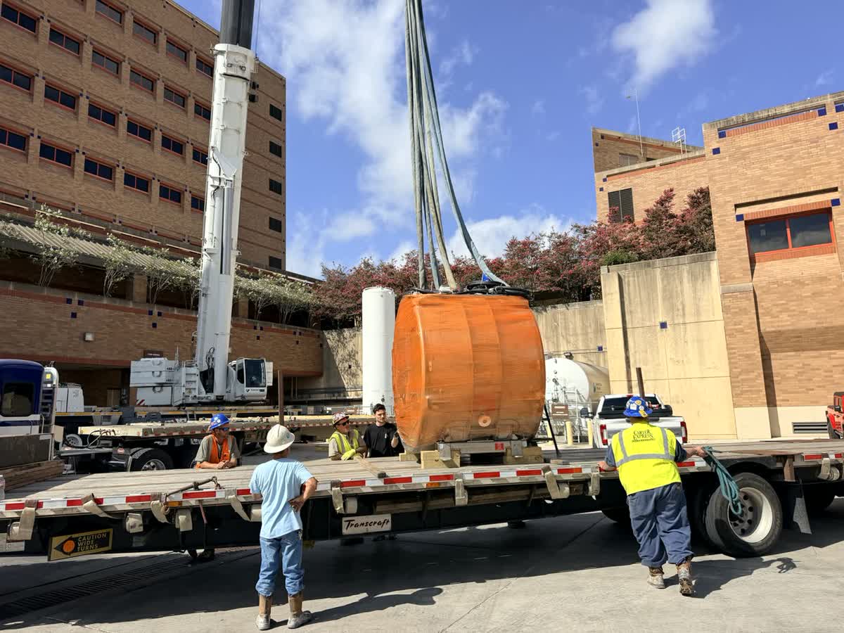 Easton crew tag-lining a unit onto a flatbed under crane