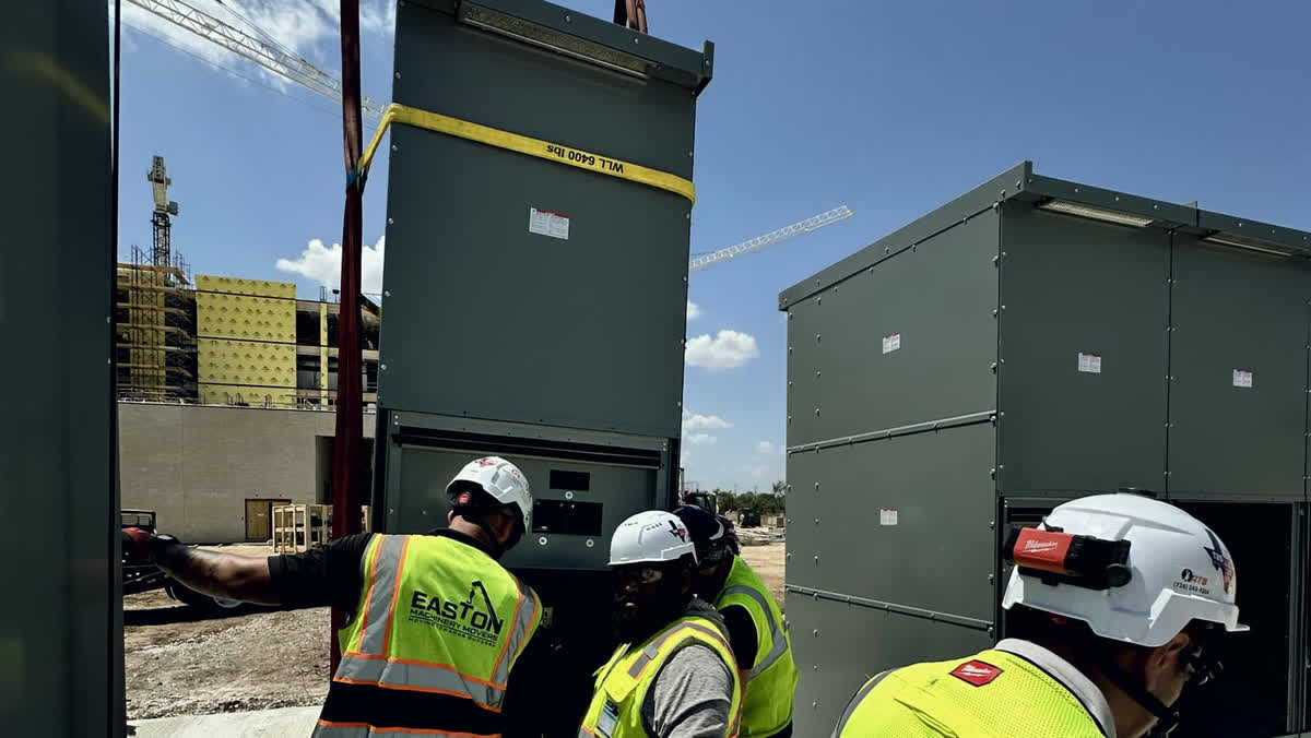 Easton crew guiding a craned load into place against the Texas sky